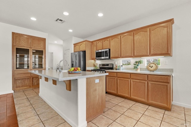 kitchen featuring a center island with sink, visible vents, stainless steel appliances, and light countertops