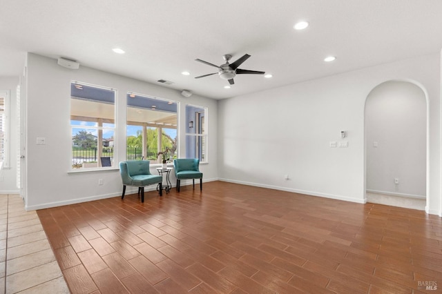 unfurnished room with arched walkways, wood finished floors, visible vents, and recessed lighting