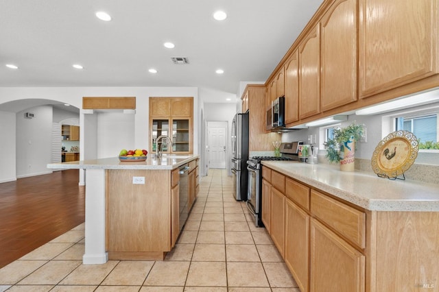 kitchen with light tile patterned floors, stainless steel appliances, a sink, visible vents, and light countertops