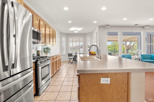 kitchen with a healthy amount of sunlight, appliances with stainless steel finishes, a sink, and light tile patterned flooring