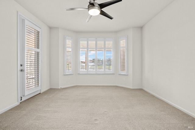 carpeted empty room featuring ceiling fan and baseboards