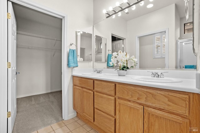 full bathroom featuring tile patterned flooring, a walk in closet, a sink, and double vanity