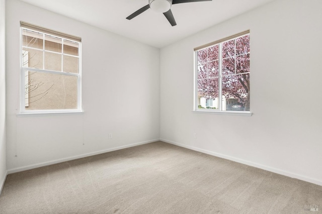 carpeted spare room featuring baseboards and a ceiling fan