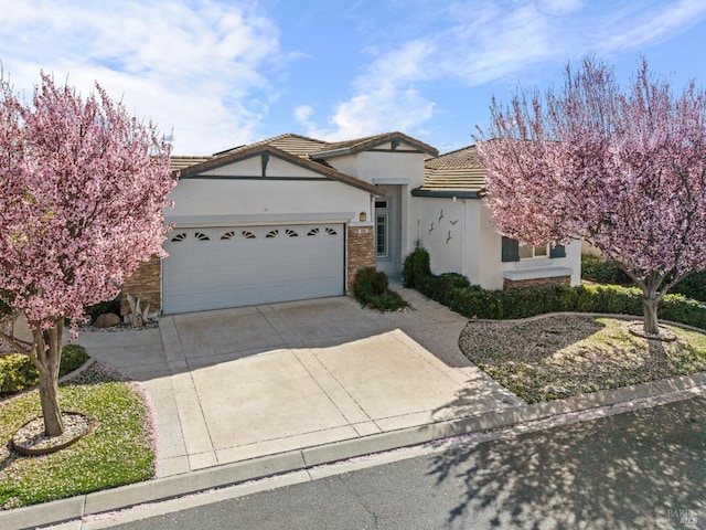 ranch-style house with concrete driveway, stone siding, a tiled roof, an attached garage, and stucco siding