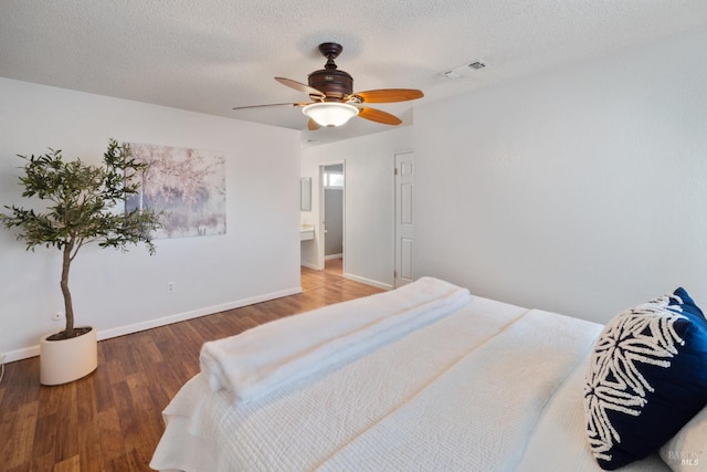 bedroom featuring a textured ceiling, ceiling fan, wood finished floors, visible vents, and baseboards