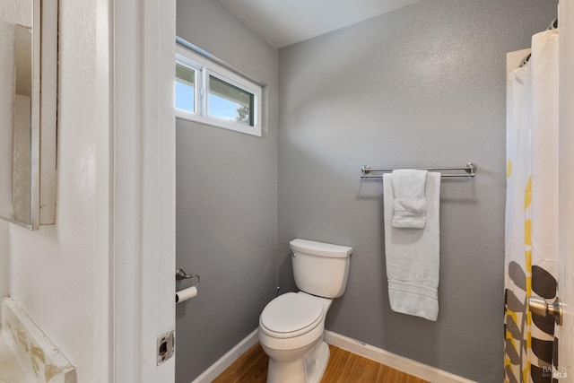 full bathroom featuring toilet, baseboards, and wood finished floors