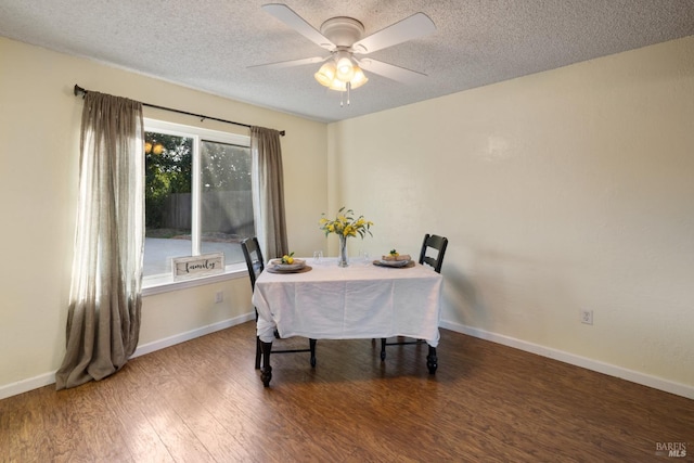 dining area featuring a textured ceiling, baseboards, and wood finished floors