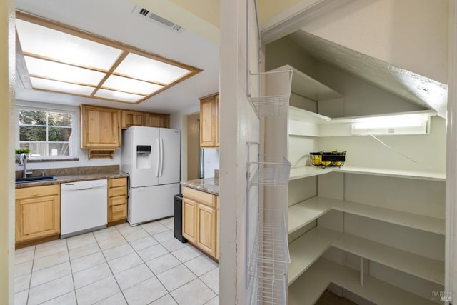 kitchen featuring white appliances, stone countertops, light tile patterned floors, visible vents, and a sink