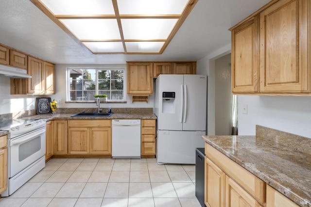 kitchen featuring light tile patterned floors, stone counters, under cabinet range hood, white appliances, and a sink