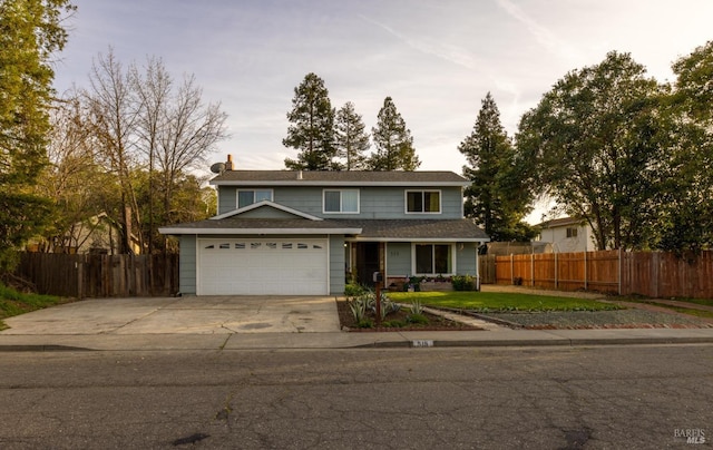 traditional-style house with a garage, a front yard, concrete driveway, and fence