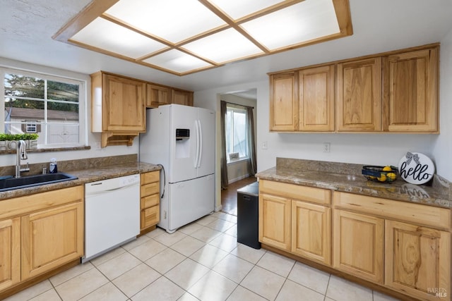 kitchen featuring light tile patterned floors, white appliances, dark countertops, and a sink