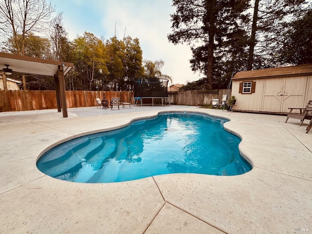 view of pool featuring a trampoline, a fenced in pool, a patio, a fenced backyard, and an outdoor structure