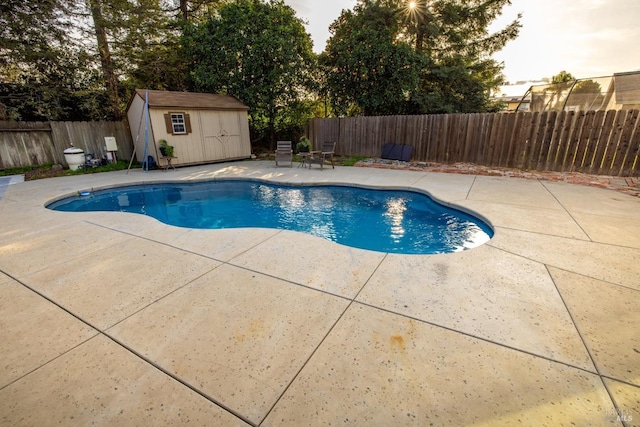 view of pool with a storage shed, a fenced in pool, a fenced backyard, an outbuilding, and a patio area