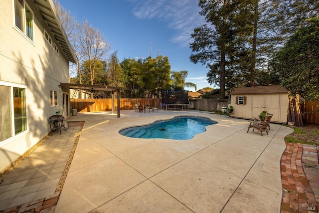 view of swimming pool with a fenced backyard, a trampoline, an outdoor structure, a patio area, and a shed