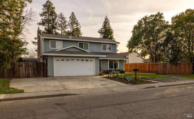 traditional home with a garage, fence, and concrete driveway