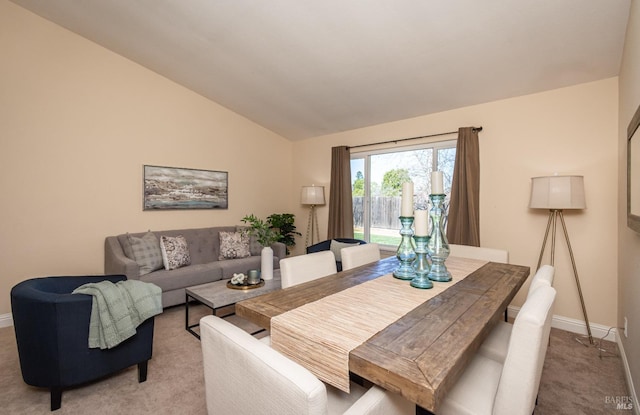 dining room with light carpet, baseboards, and vaulted ceiling