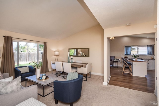 carpeted living area featuring vaulted ceiling and baseboards