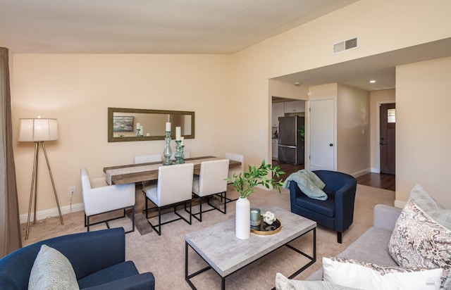 living area with lofted ceiling, baseboards, and visible vents