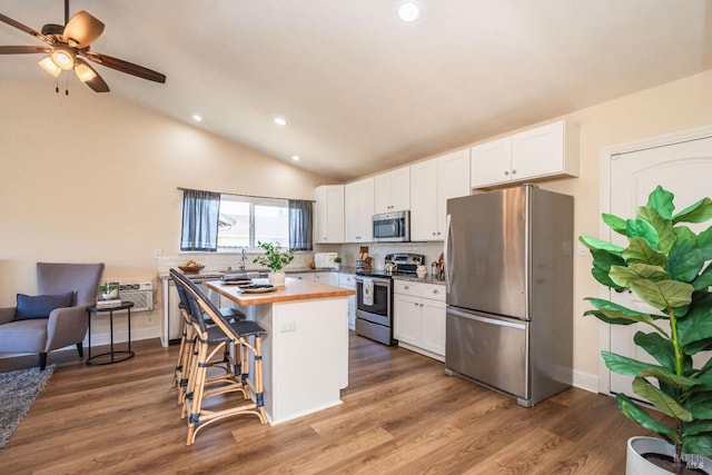 kitchen featuring stainless steel appliances, white cabinets, a kitchen island, and wooden counters