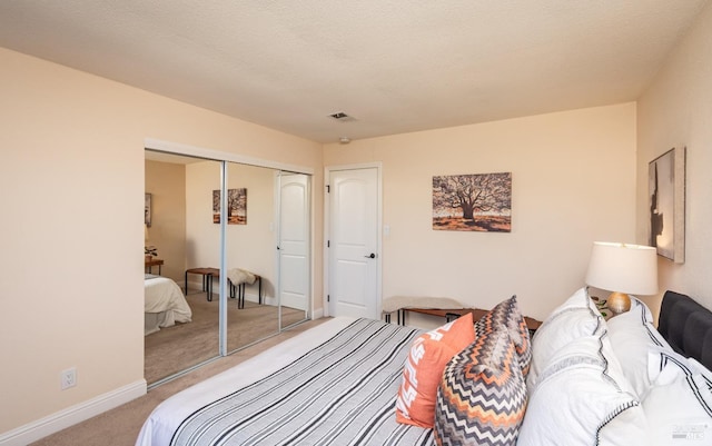 carpeted bedroom featuring visible vents, a textured ceiling, baseboards, and a closet