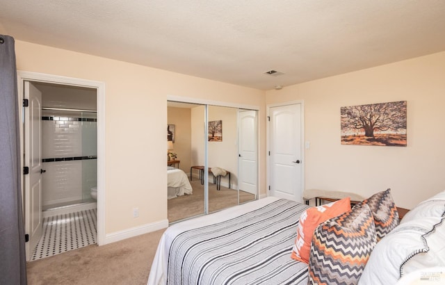 carpeted bedroom with baseboards, visible vents, ensuite bath, a textured ceiling, and a closet