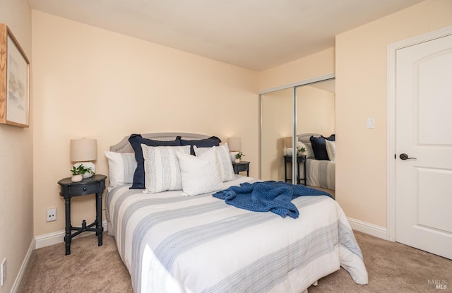 carpeted bedroom with a closet and baseboards