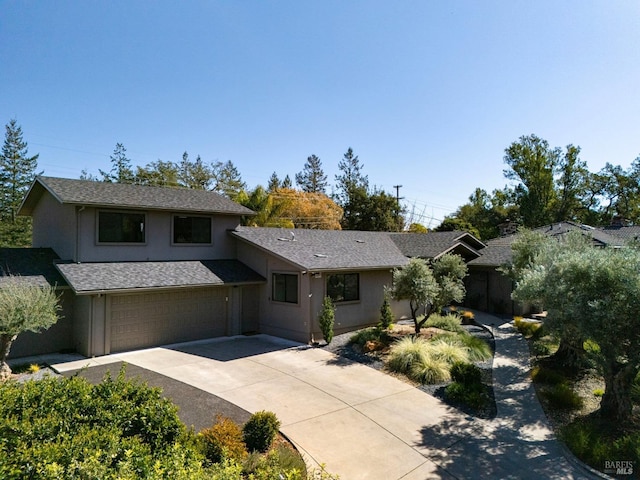 view of front of property featuring an attached garage, roof with shingles, concrete driveway, and stucco siding