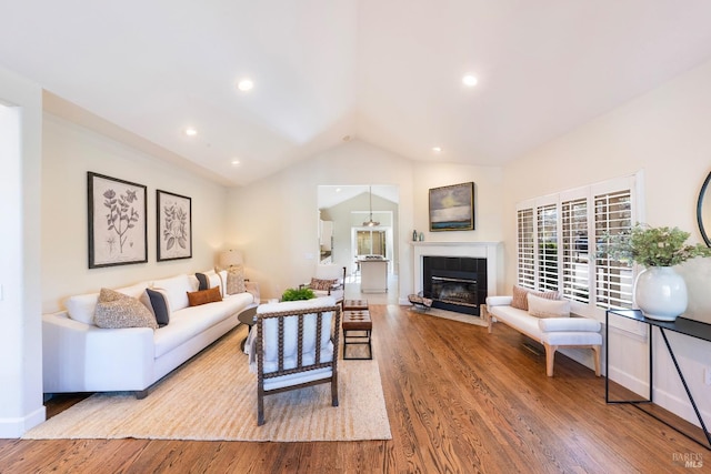 living room with vaulted ceiling, a tiled fireplace, wood finished floors, and recessed lighting