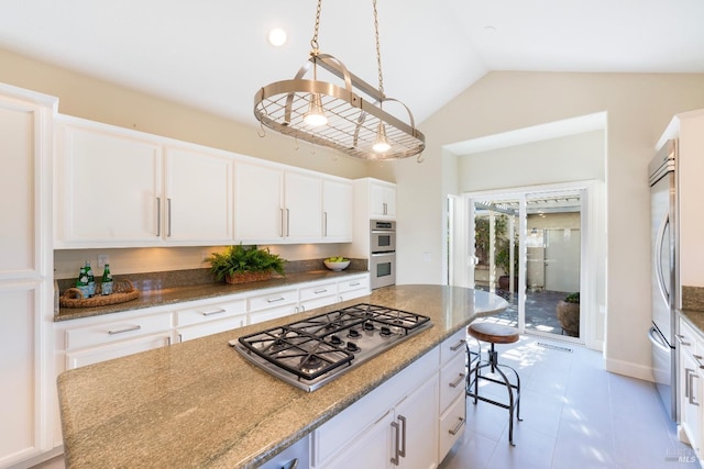 kitchen featuring stainless steel appliances, light stone counters, a breakfast bar, and white cabinets