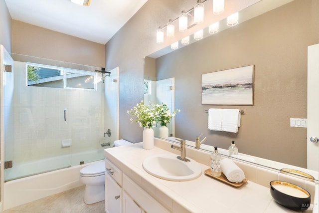 full bathroom featuring combined bath / shower with glass door, vanity, toilet, and tile patterned floors