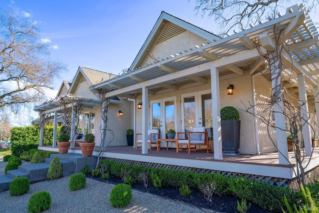 exterior space featuring french doors, stucco siding, a deck, and a pergola