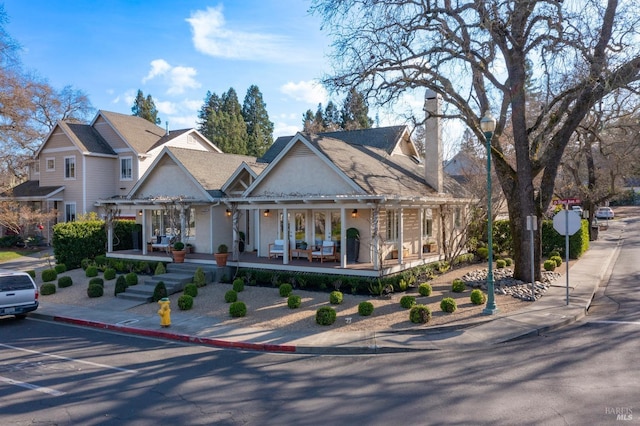 view of front of house with covered porch, a chimney, and stucco siding