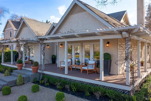 rear view of property featuring a porch, french doors, a shingled roof, and stucco siding