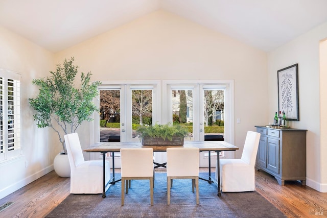 dining space featuring lofted ceiling, baseboards, wood finished floors, and french doors