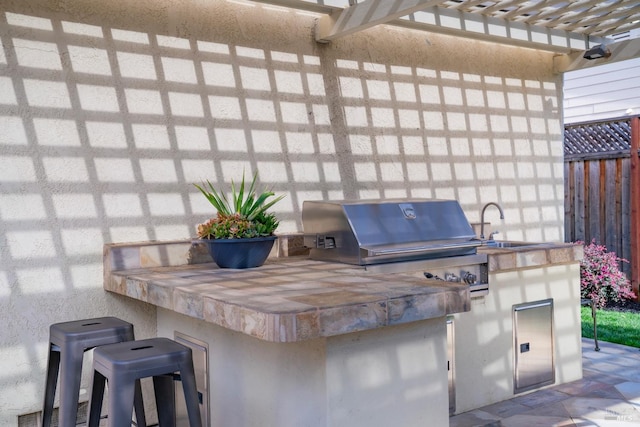 view of patio / terrace featuring a sink, fence, exterior kitchen, and area for grilling