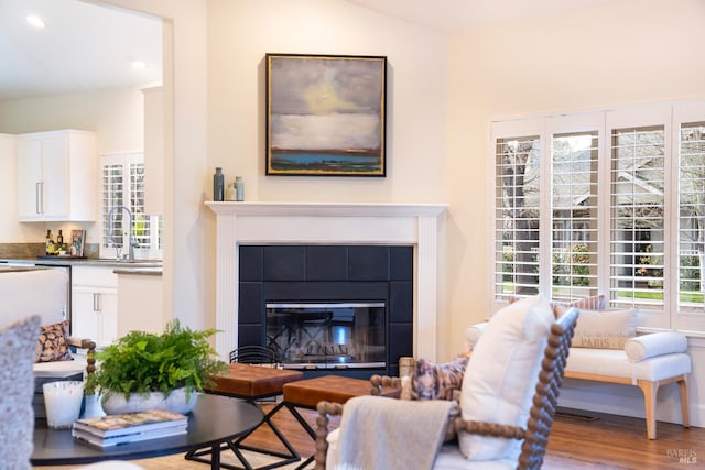 living area featuring recessed lighting, a tiled fireplace, and wood finished floors