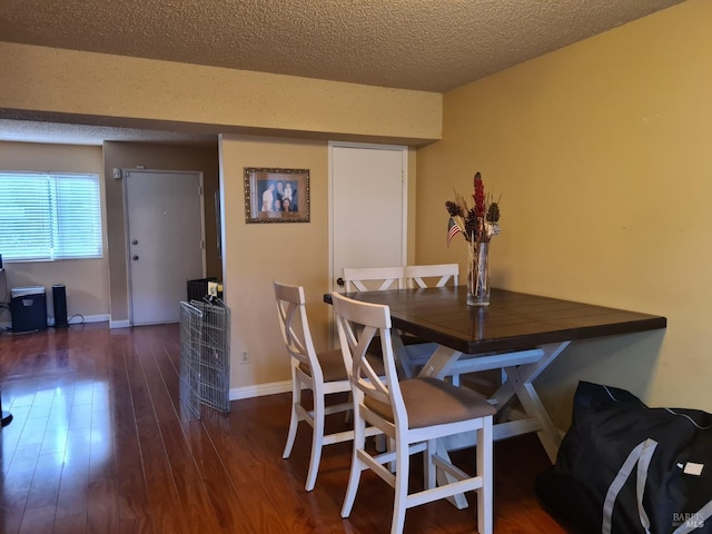 dining space with a textured ceiling, baseboards, and wood finished floors