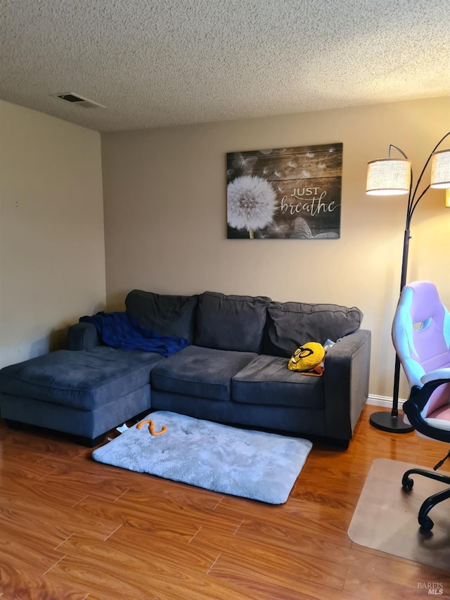 living area featuring a textured ceiling, wood finished floors, and visible vents