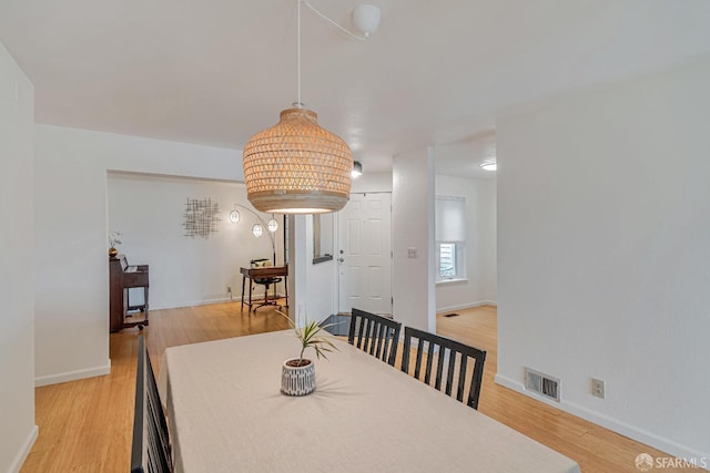 dining area with baseboards, light wood-style flooring, and visible vents