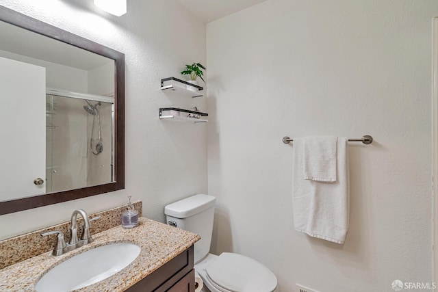 bathroom with toilet, a shower stall, and vanity