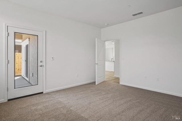 carpeted empty room featuring visible vents and baseboards