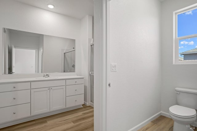 full bathroom featuring baseboards, toilet, wood finished floors, vanity, and a shower stall