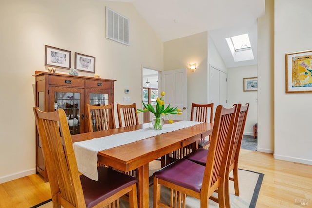 dining area featuring baseboards, light wood-style floors, visible vents, and a skylight