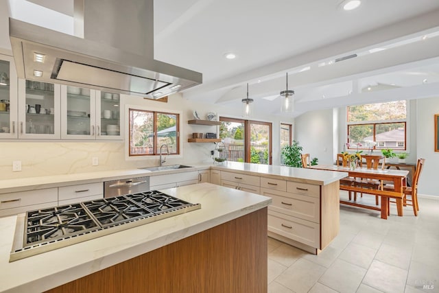 kitchen featuring wall chimney range hood, stovetop, a sink, and plenty of natural light