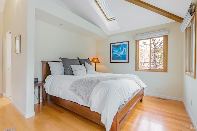 bedroom with vaulted ceiling with skylight, light wood-style flooring, visible vents, and baseboards