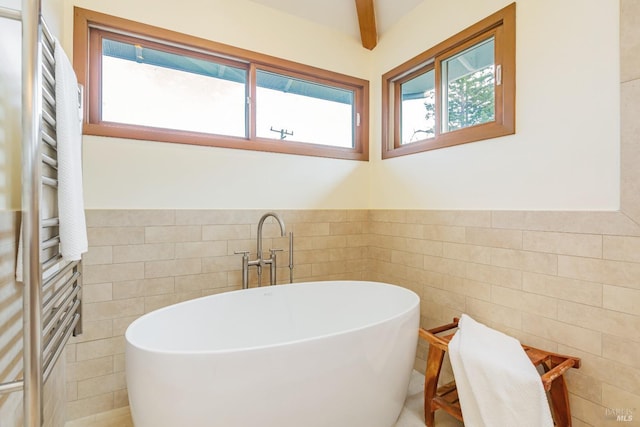 bathroom with a freestanding bath, tile walls, a wainscoted wall, and plenty of natural light