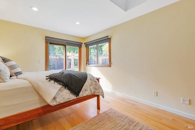 bedroom with light wood-style flooring, baseboards, recessed lighting, and access to exterior