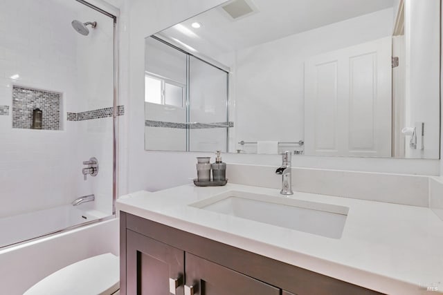 bathroom featuring shower / bath combination with glass door, visible vents, toilet, and vanity