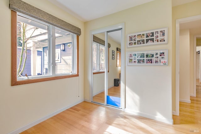 interior space featuring light wood-style flooring, a closet, baseboards, and multiple windows