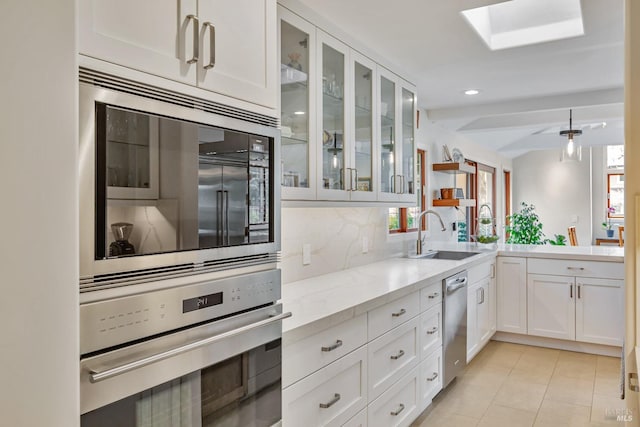 kitchen with white cabinets, stainless steel appliances, a sink, and a wealth of natural light